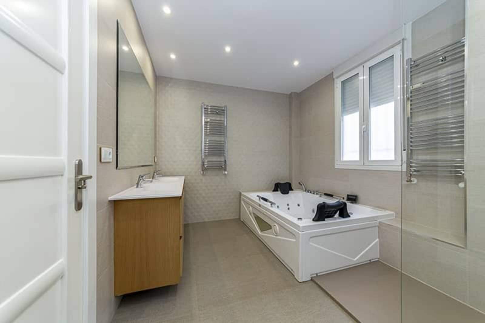 Baño amplio con bañera de hidromasaje y revestimiento beige.. Fotografía 16